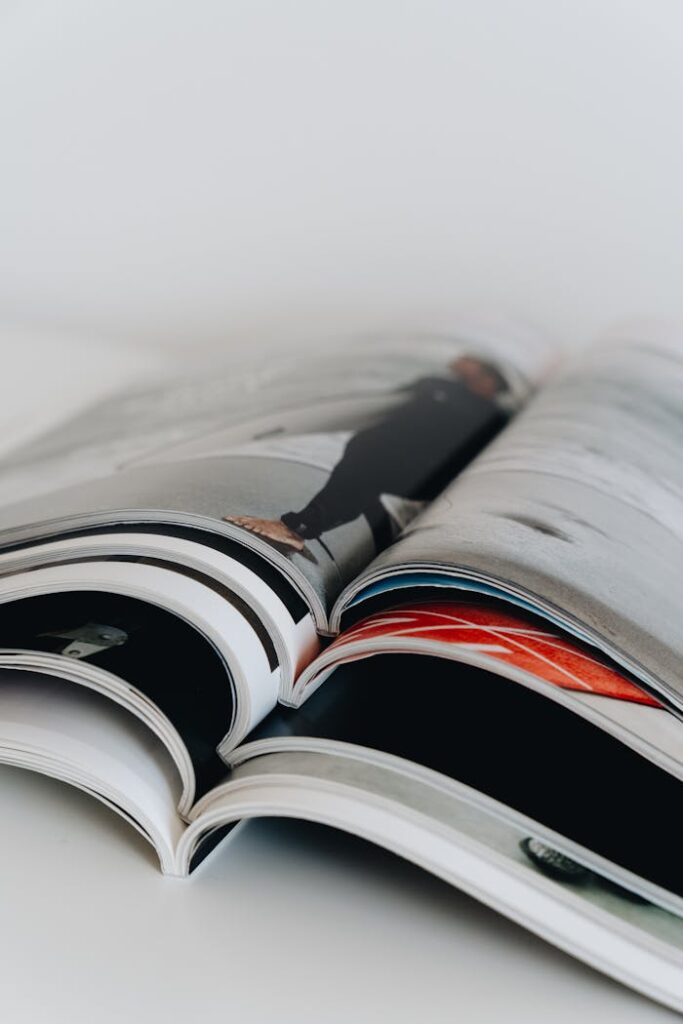 Vertical stack of open magazines showcasing various colorful pages in an artistic composition.