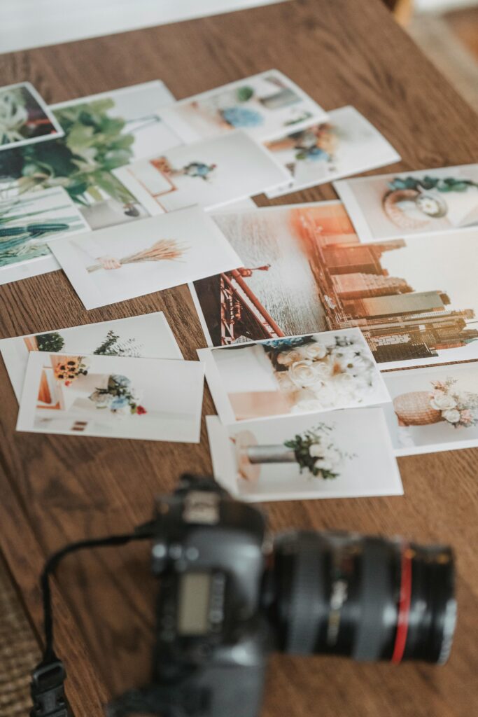 High angle many printed photos scattered on wooden table near professional photo camera in light room